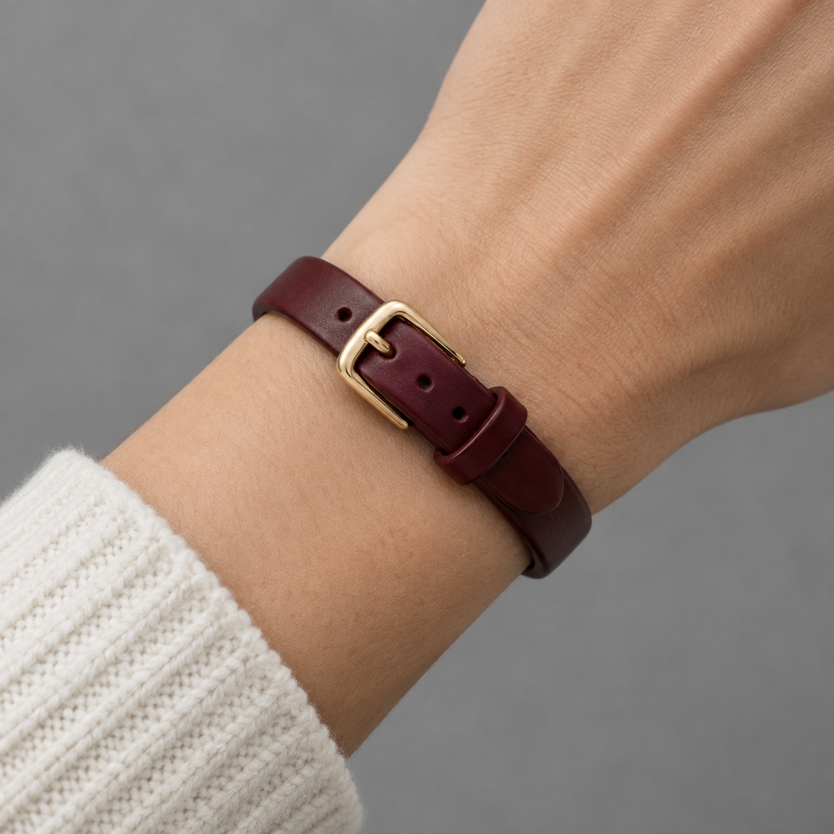 Close-up of the gold-tone buckle and pin on the burgundy bracelet