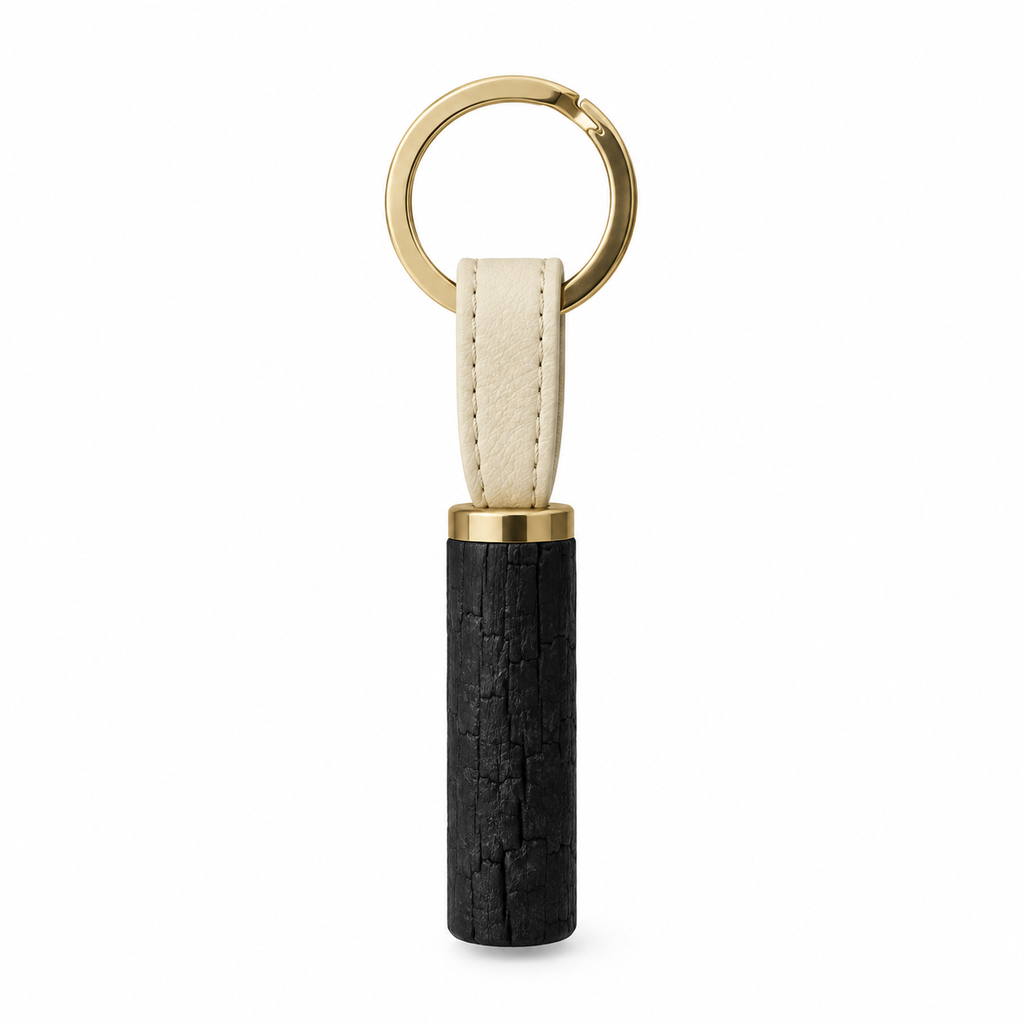 Front view of charcoal keychain with gold ring and leather strap.